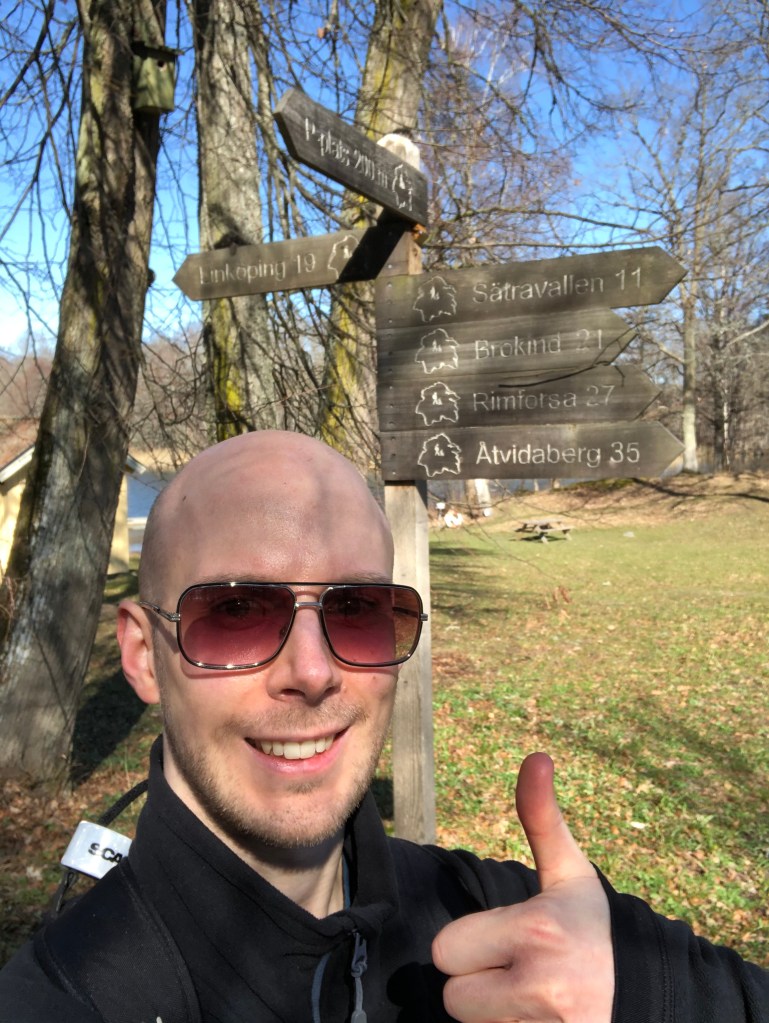 Selfie i Bjärka-Säby med vägskyltar till Linköping och Rimforsa, Åtvidaberg m.m. i bakgrunder.