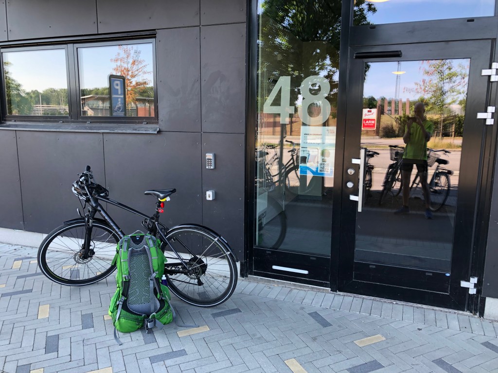 Bild på min cykel och min ryggsäck utanför porten till min lägenhet