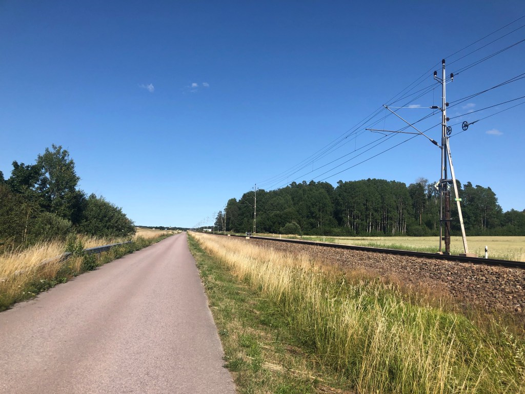Liten bilväg jämte tågrälsen mellan Köping och Munktorp.