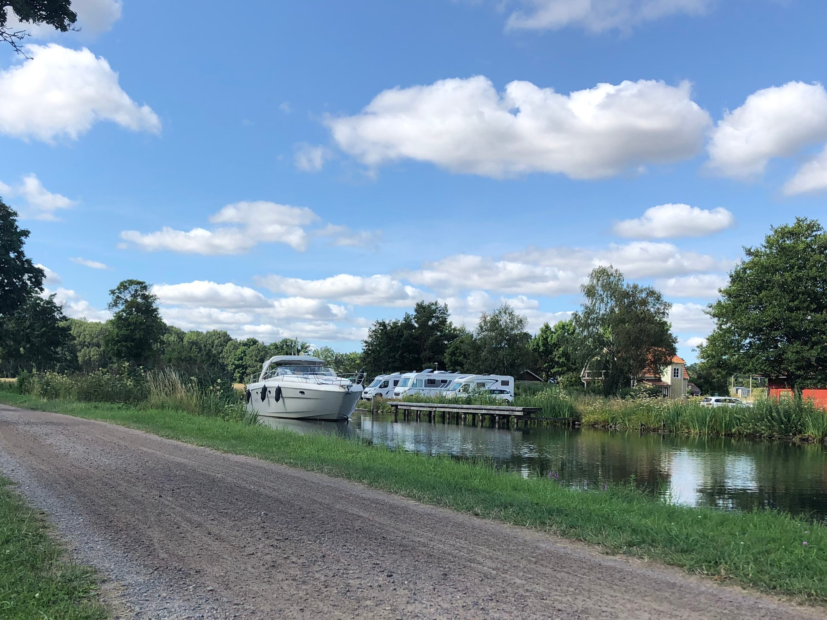 Göta kanal med en förbipasserande båt och cykelvägen bredvid