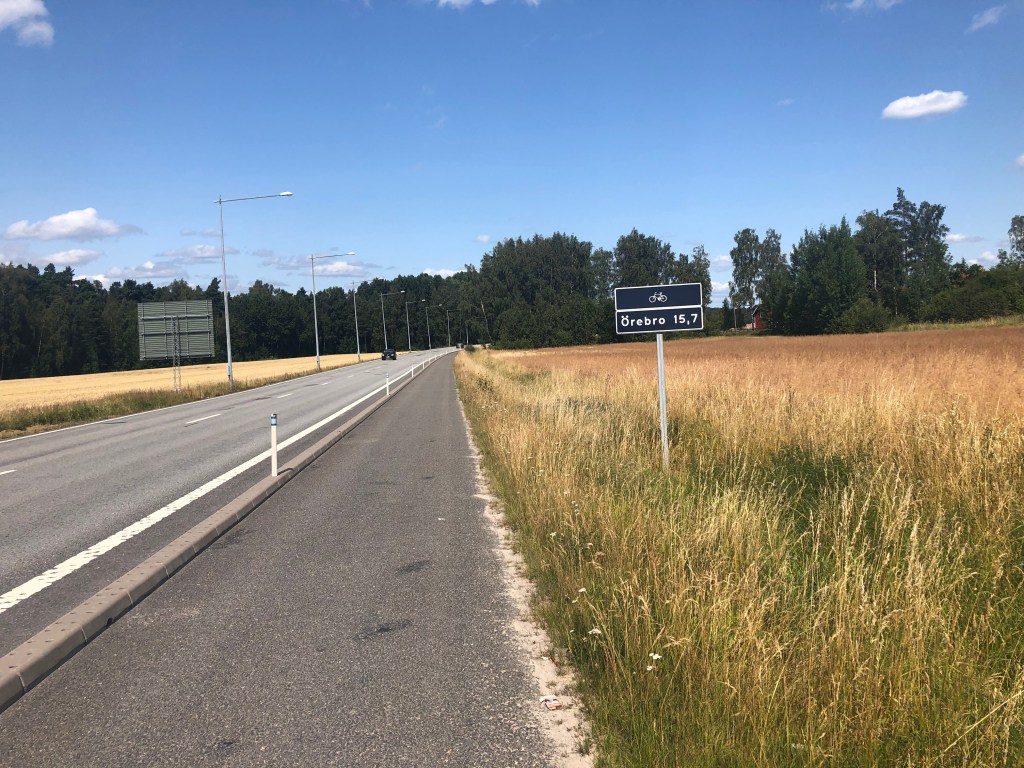 Skylt som visar 15,7 km till Örebro längs med Kumlavägen.
